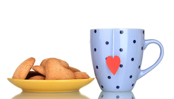 stock image Blue cup with tea bag and heart-shaped cookies on yellow plate isolated on