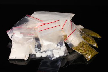 Cocaine and marihuana in packages on black background clipart