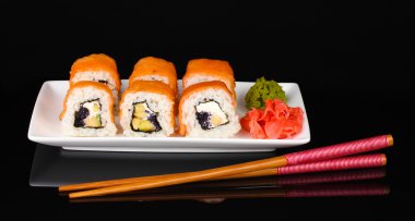 Tasty rolls served on white plate with chopsticks isolated on black clipart