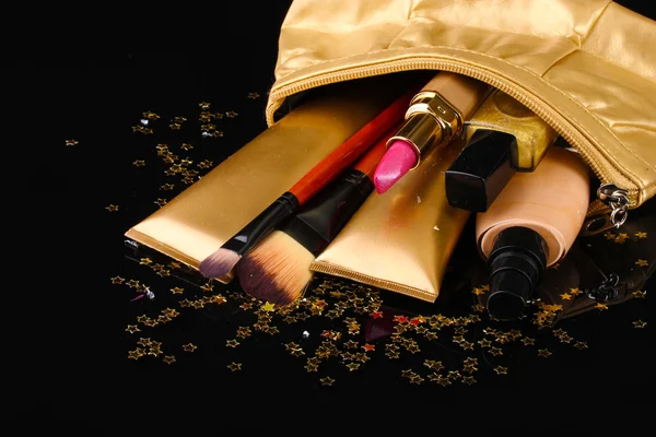 Bolsa de maquiagem dourada bonita e cosméticos isolados em preto — Fotografia de Stock