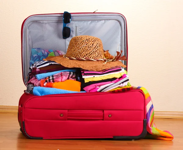Open red suitcase with clothing in the room — Stock Photo, Image