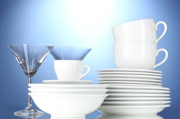 Порожні миски, тарілки, чашки та окуляри на синьому фоні — стокове фото