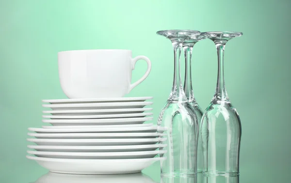 Piatti puliti, tazza e bicchieri su sfondo verde — Foto Stock