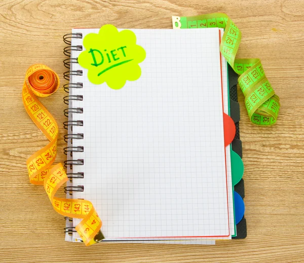 Planowania diety. taśmy pomiarowe notatnik i długopis na drewnianym stole — Zdjęcie stockowe