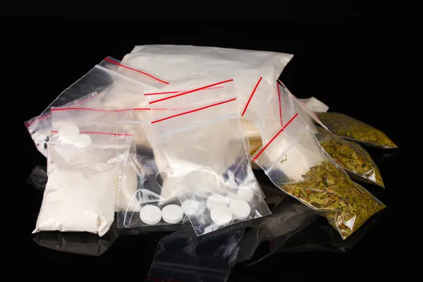 Cocaína y marihuana en paquetes sobre fondo negro — Foto de Stock