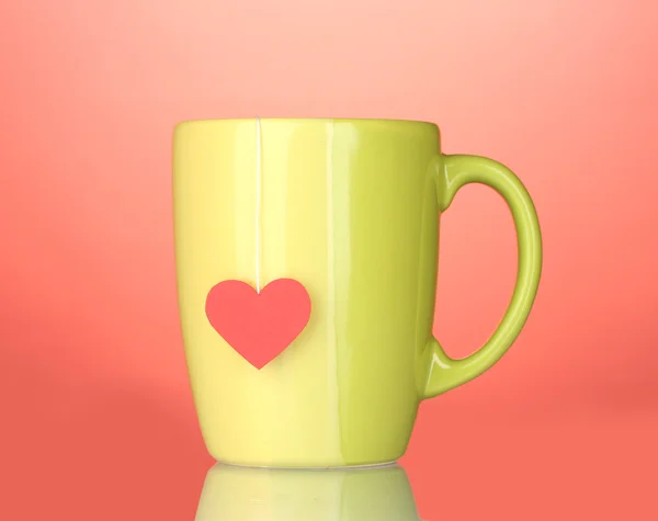 Taza verde y bolsa de té con etiqueta roja en forma de corazón sobre fondo rojo —  Fotos de Stock