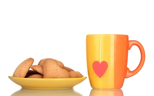 Pomarańczowy kubek z torebki herbaty i ciasteczek w kształcie serca na na białym tle o żółte płytki — Zdjęcie stockowe