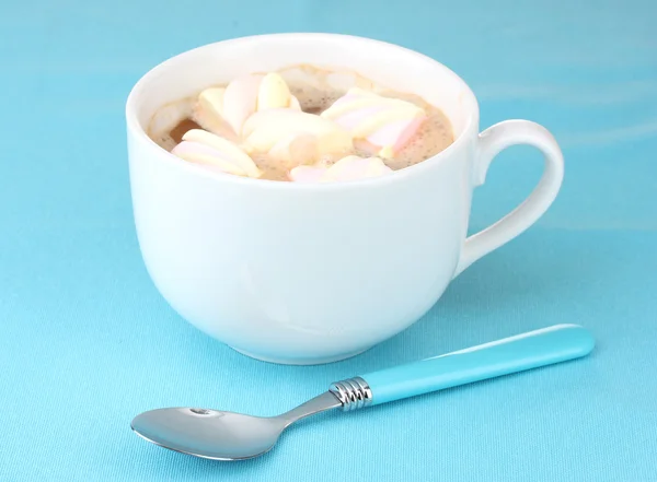 Tasse Cappucino mit Marshmallows und Löffel auf blauem Hintergrund — Stockfoto