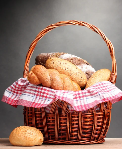 在灰色的背景上的木桌上的篮子里的美味面包 — 图库照片