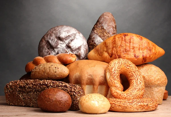 灰色の背景に木製のテーブル上に美味しいパン — ストック写真