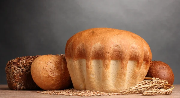 Läckra bröd och öron på träbord på grå bakgrund — Stockfoto