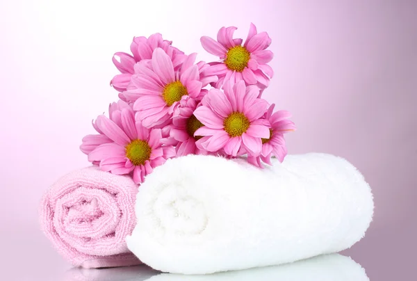 Asciugamani e bellissimi fiori su sfondo rosa — Foto Stock
