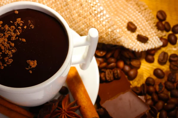 Kubek gorącej czekolady, cynamonu, orzechów i czekolady na drewnianym stole — Zdjęcie stockowe
