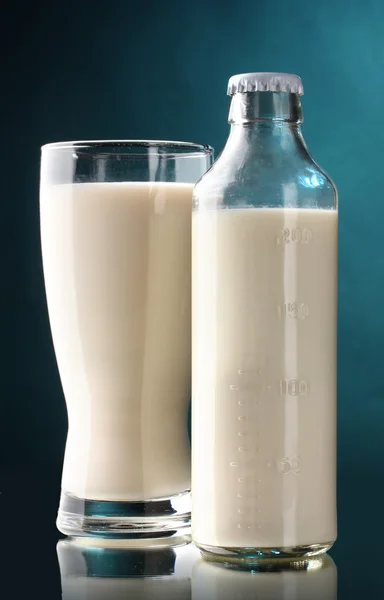 Butelkę i kieliszek mleka na niebieskim tle — Zdjęcie stockowe