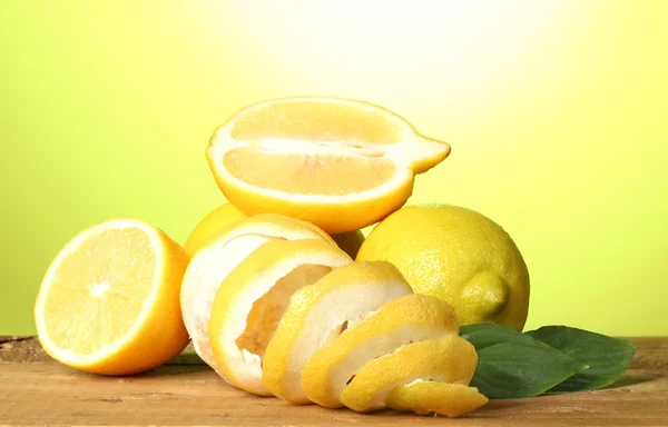 Ripe lemons with leaves on wooden table on green background — Stock Photo, Image