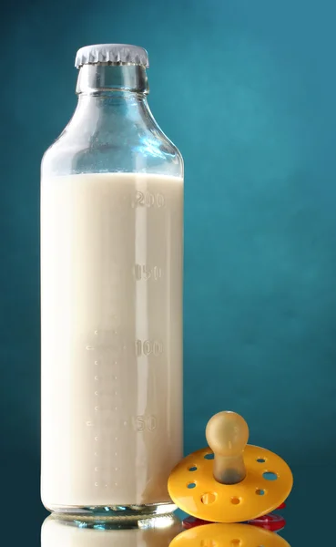 Μπουκάλι γάλα και πιπίλα σε μπλε φόντο — Φωτογραφία Αρχείου