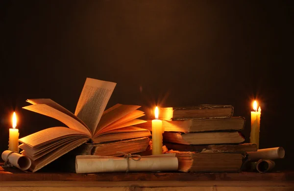Hromadu starých knih s svíčku a posun ve tmě — Stock fotografie