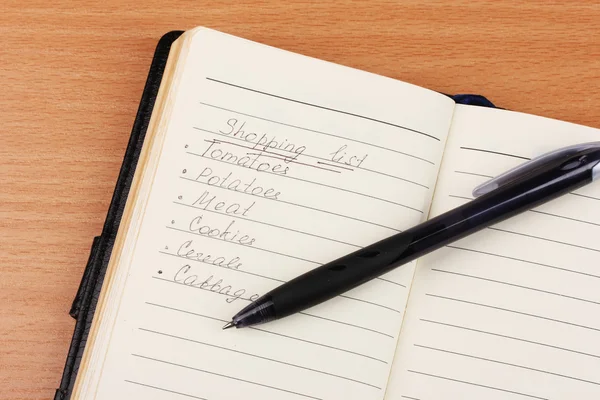 Shoping listesi ve ahşap masa üstünde kalem — Stok fotoğraf