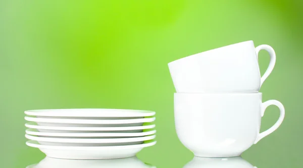 Clean plates and cups on green background — Stock Photo, Image