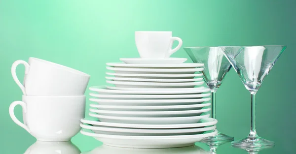 Piatti puliti, tazze e bicchieri su sfondo verde — Foto Stock