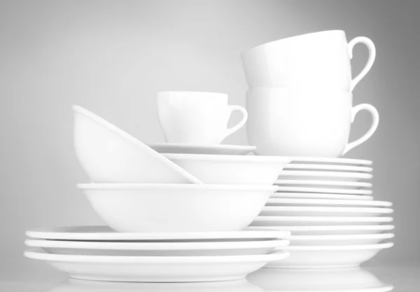 Ciotole vuote, piatti e tazze su sfondo grigio — Foto Stock