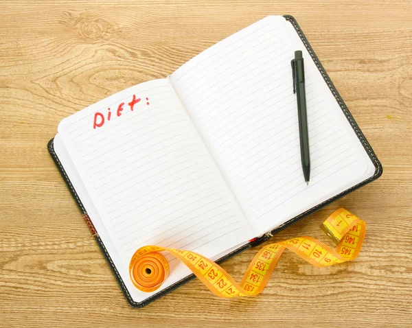 Planning van dieet. meten tapes van de notebook en pen op houten tafel — Stockfoto