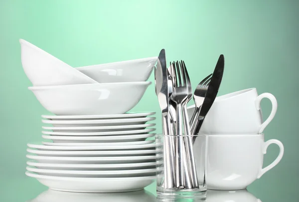 Limpia platos, tazas y cubiertos sobre fondo verde —  Fotos de Stock