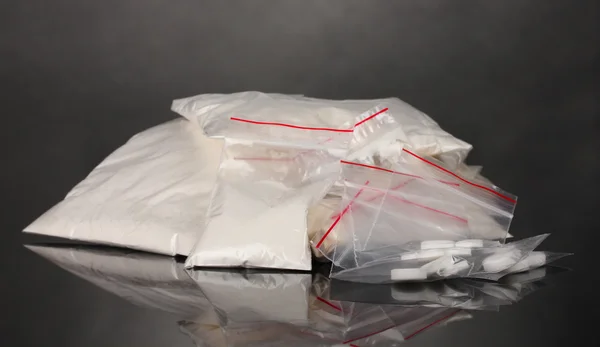 Cocaína e drogas em embalagens de fundo cinzento — Fotografia de Stock