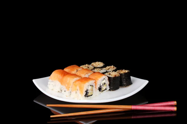 Tasty rolls served on white plate with chopsticks isolated on black — Stock Photo, Image