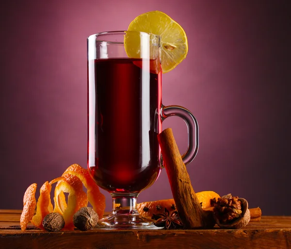 Glühwein in het glas, specerijen en citroen op paarse achtergrond — Stockfoto