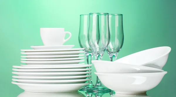 Platos limpios, taza y vasos sobre fondo verde — Foto de Stock