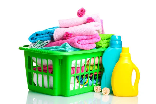 Waschmittel und Handtücher in grünem Plastikkorb isoliert auf weiß — Stockfoto