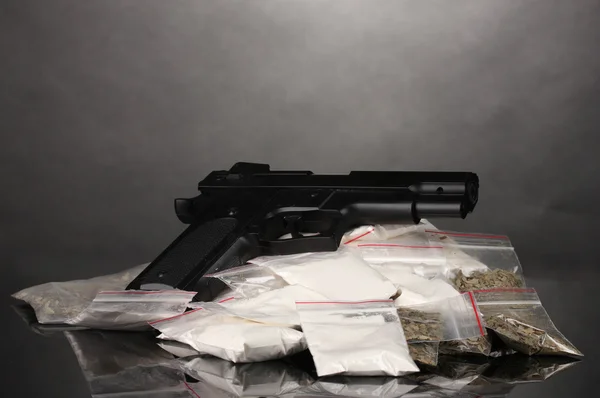 Kokaint és marihuánát csomagok és a pisztolyt a szürke háttér — Stock Fotó