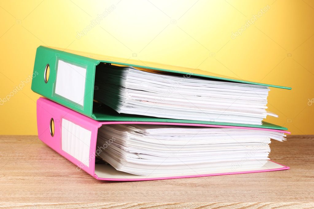 Bright office folders on wooden table on yellow background