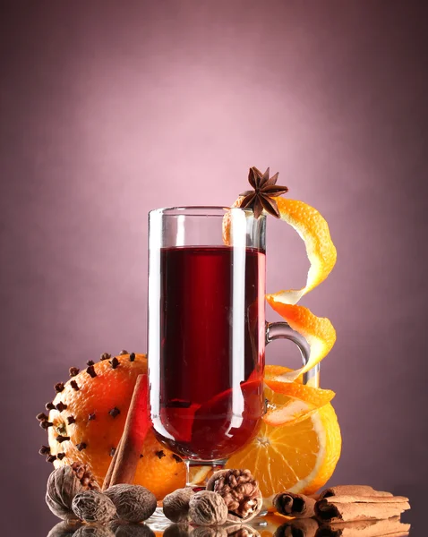 Vino caliente en la copa, especias y naranja sobre fondo púrpura —  Fotos de Stock