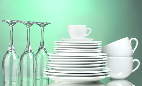 Schone borden, kopjes en glazen op groene achtergrond — Stockfoto