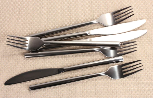 Forks and knives on a beige tablecloth — Stock Photo, Image