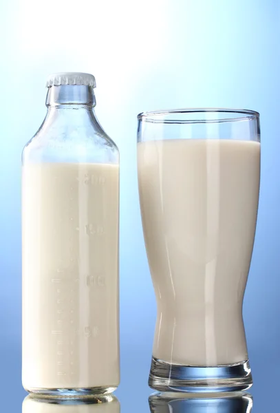 Garrafa e vidro de leite no fundo azul — Fotografia de Stock