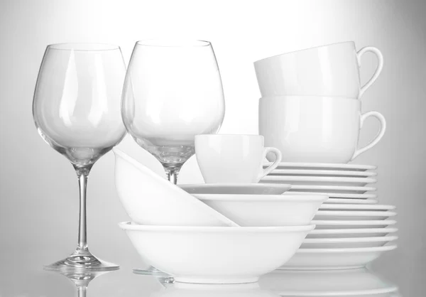 Пустые миски, тарелки, чашки и стаканы на сером фоне — стоковое фото