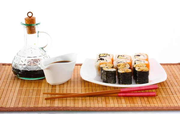 Lekkere broodjes geserveerd op wit bord met stokjes en soja saus op bamboe m — Stockfoto
