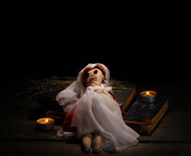 Voodoo doll girl-bride on a wooden table in the candlelight clipart