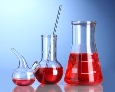 Three flasks with red liquid with reflection on blue background clipart