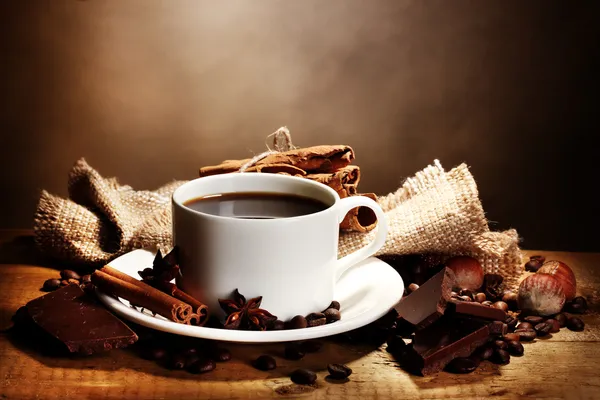 Kahve Kupası ve fasulye, tarçın, fındık ve çikolata ahşap masa o — Stok fotoğraf