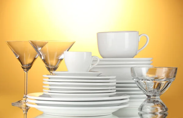 Ciotole vuote, piatti, tazze e bicchieri su sfondo giallo — Foto Stock