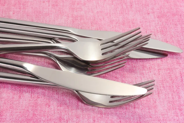 Garfos e facas em uma toalha de mesa rosa — Fotografia de Stock