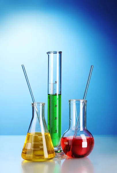 Tres frascos con líquido de color con reflexión sobre fondo azul — Foto de Stock