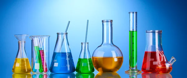 Laboratorní sklo barevné kapalinou a s odrazem na blu — Stock fotografie
