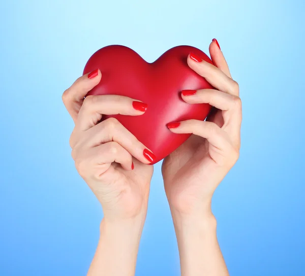 Czerwone serce w ręce kobiety na niebieskim tle — Zdjęcie stockowe