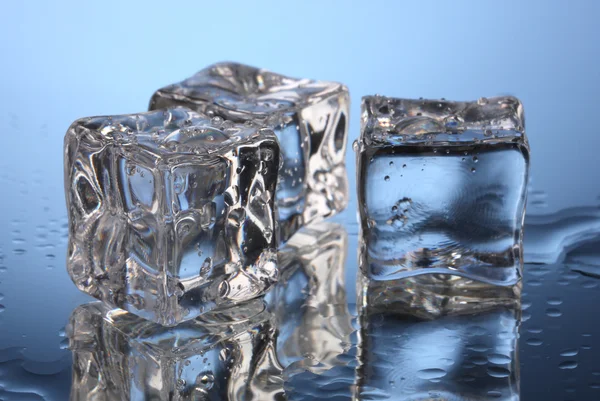 Smeltende ijsblokjes op blauwe achtergrond — Stockfoto