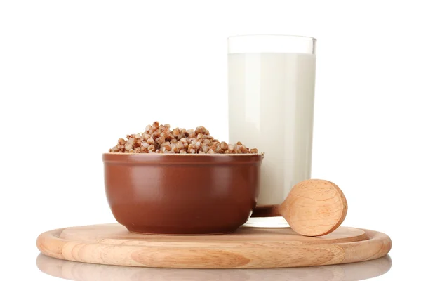 Trigo sarraceno hervido en un bol marrón un vaso de leche en una tabla de madera aislada —  Fotos de Stock